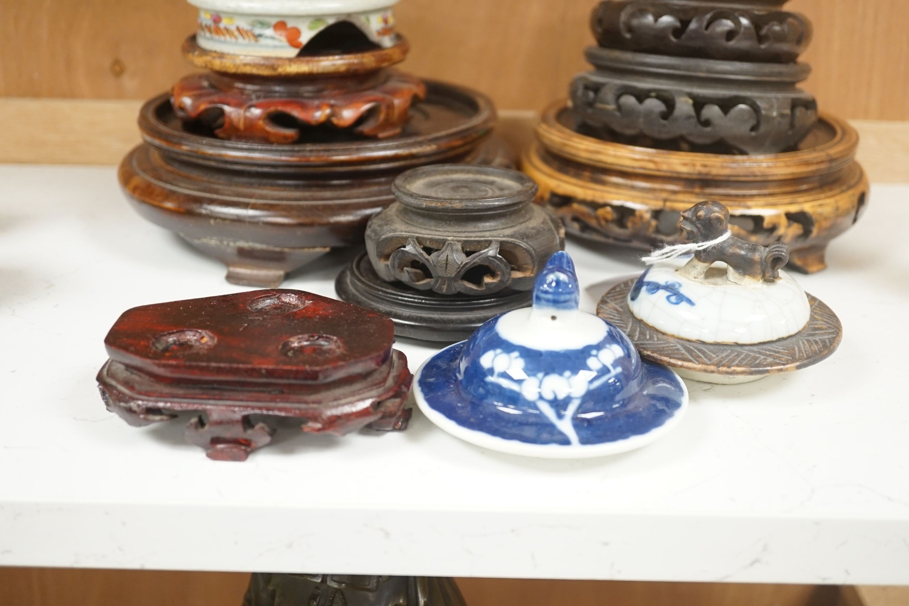 A group of Chinese wooden stands and three ceramics covers.